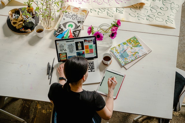 Woman studying at laptop with tablet